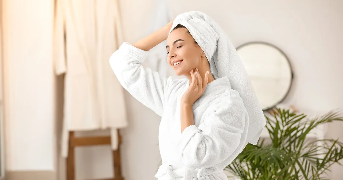 Frau im Bademantel in hellem Badezimmer