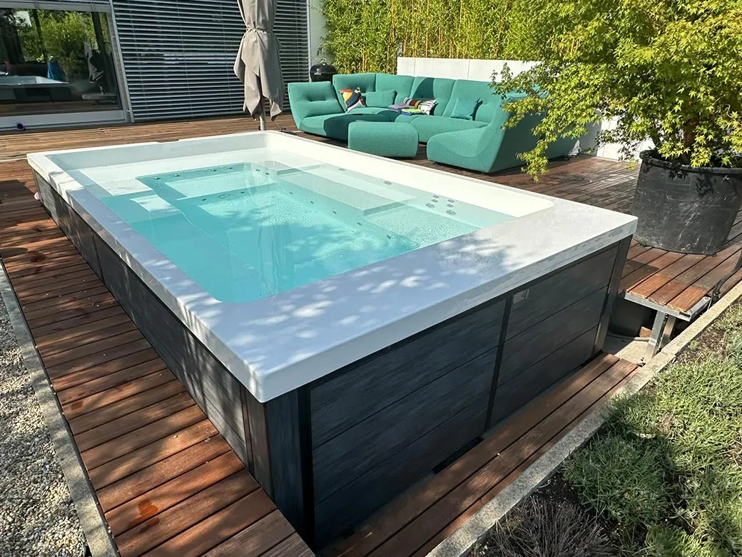 Lagoon Spa mit klaren Linien und Holzdeck, eingebettet in eine stilvolle Gartenlounge mit großzügiger Sitzfläche.