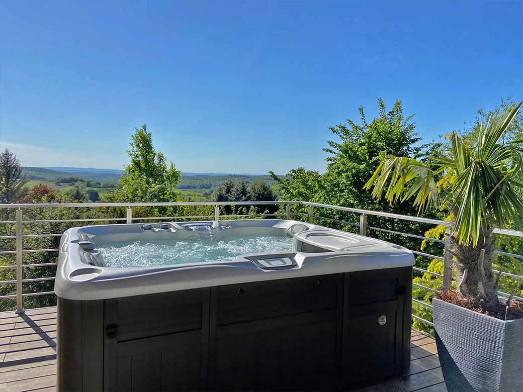 Whirlpool Capri auf Balkonterrasse mit Panoramablick ins Grüne und dekorativer Palme.