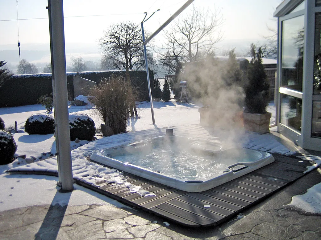 Eingelassener Whirlpool im Außenbereich bei Schnee – warmes Sprudelwasser sorgt für winterliche Wellnessmomente.